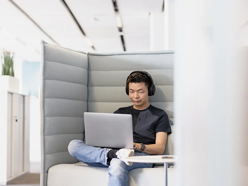 En Henkel-medarbejder med høretelefoner arbejder koncentreret om sin bærbare computer. 