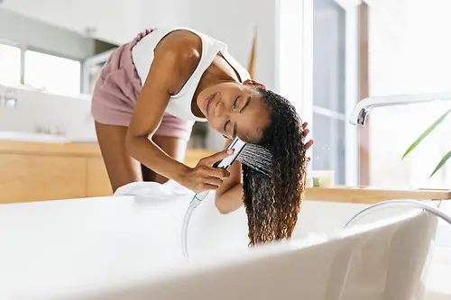 Kvinner på badet vasker det brune lange håret i badekar